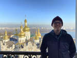 Student smiling at camera with a golden-domed church in the background